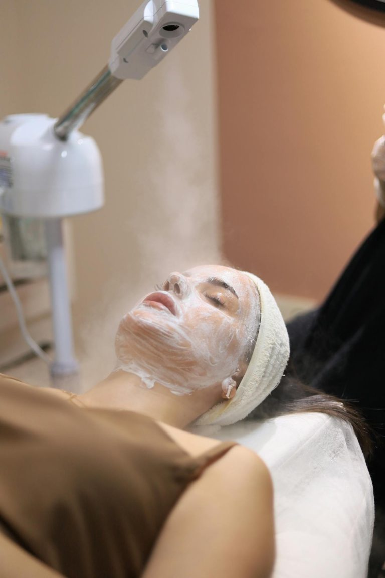 Woman enjoying a facial steam treatment in a serene spa setting.