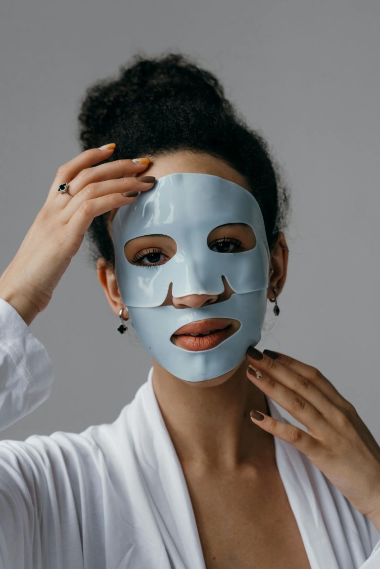 Woman enjoying a facial treatment with a blue sheet mask for skincare routine.